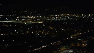 AX69_157 - 4.8K aerial stock footage track small airplane flying over Pacoima homes at night, California