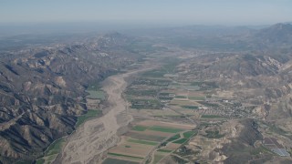 AX70_185 - 4K aerial stock footage Flyby farm fields and Santa Clara River surrounded by mountains in Piru, California