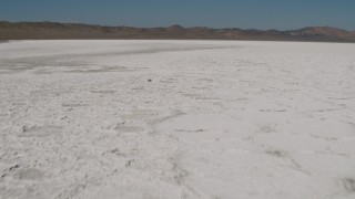 4K aerial stock footage Fly low over the surface of Soda Lake, California and tilt to reveal mountains Aerial Stock Footage | AX70_209