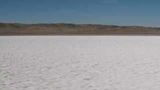 AX70_213 - 4K aerial stock footage Fly low over Soda Lake with a view of desert mountains in California