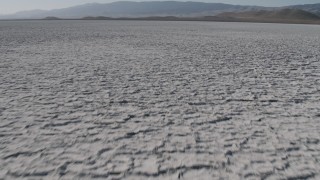 4K aerial stock footage Fly low over Soda Lake in California, and tilt to reveal desert mountains Aerial Stock Footage | AX70_216