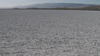 4K aerial stock footage Tilt from a close-up of the surface of Soda Lake in California, and reveal desert mountain range Aerial Stock Footage | AX70_219