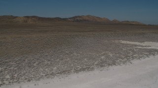 4K aerial stock footage Fly over Soda Lake and a desert road in California to approach desert mountains Aerial Stock Footage | AX70_223