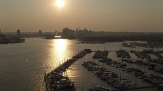 AX73_148 - 5.1K aerial stock footage flying over Baltimore Marine Center to approach Downtown Baltimore skyline at sunset, Maryland