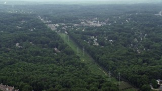 4.8K aerial stock footage of rows of power lines on a green strip between trees and suburbs in Burke, Virginia Aerial Stock Footage | AX74_135