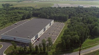 AX75_176 - 4.8K aerial stock footage flying over warehouse buildings to approach hangars at Manassas Regional Airport