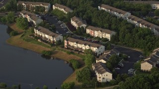 4.8K aerial stock footage flying by waterfront town houses beside pond, Manassas, Virginia, sunset Aerial Stock Footage | AX76_002