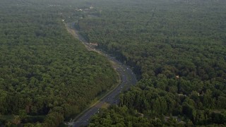 AX76_014 - 4.8K aerial stock footage flying by Ox Road, dense forest, Fairfax Station, Virginia, sunset