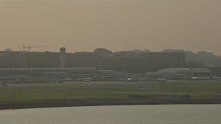 AX76_038 - 4.8K aerial stock footage flying by Ronald Reagan Washington National Airport, Arlington, Virginia, sunset