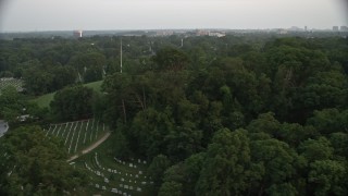 4.8K aerial stock footage of gravestones and trees at Arlington National Cemetery, Virginia, twilight Aerial Stock Footage | AX76_116