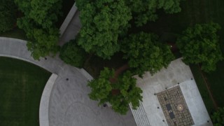 AX76_117 - 4.8K aerial stock footage flying over Arlington National Cemetery trees to reveal President John F. Kennedy Gravesite, Virginia, twilight