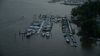 AX76_174 - 4.8K aerial stock footage flying by docked boats at a marina on the Potomac River, Washington, D.C., twilight