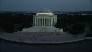 AX76_184 - 4.8K aerial stock footage of the Jefferson Memorial, lit up for the night, with tourists on the steps, Washington, D.C., twilight