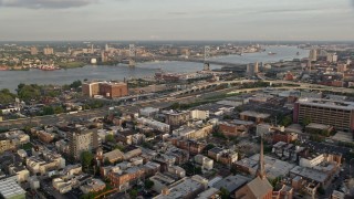 AX80_072 - 4.8K aerial stock footage of Benjamin Franklin Bridge and Delaware River seen from I-95 in North Philadelphia, Pennsylvania, Sunset