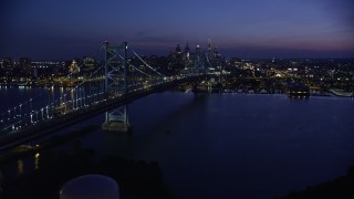 AX81_007E - 4.8K aerial stock footage approaching Benjamin Franklin Bridge, Delaware River, and Downtown Philadelphia skyline, Pennsylvania, Night