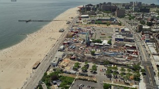 AX83_215E - 4.8K aerial stock footage orbiting Luna Park and the boardwalk beside Coney Island Beach, Brooklyn, New York City