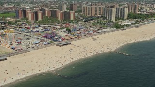 4.8K aerial stock footage flying by Luna Park, Riegelmann Boardwalk, and Coney Island Beach sunbathers, Brooklyn, New York City Aerial Stock Footage | AX83_220E