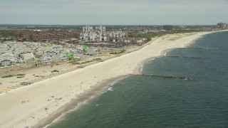 AX83_230E - 4.8K aerial stock footage flying by beachfront condos and sunbathers, Far Rockaway, New York