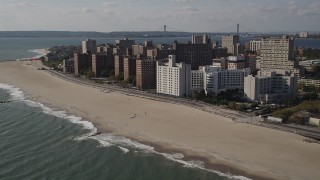 4K aerial stock footage of passing by Coney Island Beach and apartment buildings, Brooklyn, New York Aerial Stock Footage | AX88_063