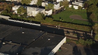 4K aerial stock footage Tracking a commuter train passing through, Jersey City, New Jersey, sunrise Aerial Stock Footage | AX90_163