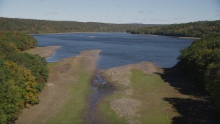 4K aerial stock footage of approaching the shore surrounded by fall foliage, Lake Gallard, Connecticut Aerial Stock Footage | AX91_160