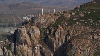 AXSF03_004 - 5K aerial stock footage flying by Dynegy Morro Bay power plant, eclipsed by Morro Rock, Morro Bay, California