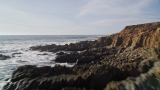 AXSF03_019 - 5K aerial stock footage of flying low over waves crashing into coastal cliffs, Harmony, California