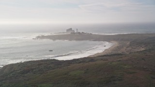 AXSF03_054 - 5K aerial stock footage tilt from Highway 1 to reveal Piedras Blancas Light Station, Point Piedras Blancas, California