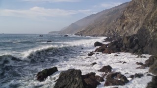 AXSF03_064 - 5K aerial stock footage Fly low over ocean waves, rocks, by coastal cliffs, San Simeon, California