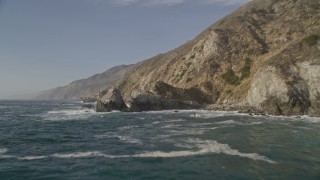 5K aerial stock footage of flying low over waves by coastal cliffs and rock formations, Big Sur, California Aerial Stock Footage | AXSF03_097