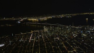 AXSF07_073 - 5K aerial stock footage of a high altitude view of Coit Tower, the Bay Bridge, and skyscrapers in Downtown San Francisco, California, night