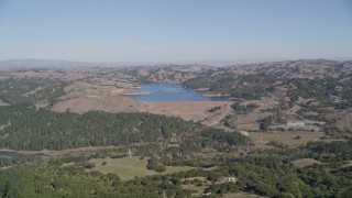 AXSF08_012 - 5K aerial stock footage of flying over a dirt road and trees to reveal Briones Reservoir, Orinda, California