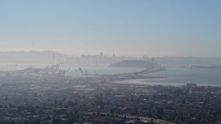 5K aerial stock footage a wide hazy view of Port of Oakland, Bay Bridge, and Downtown San Francisco skyline, California Aerial Stock Footage | AXSF09_014