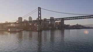 AXSF10_001 - 5K aerial stock footage fly low over the bay to approach and ascend over Bay Bridge toward Downtown San Francisco, California, sunset