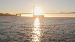 5K aerial stock footage low approach to a cargo ship near Golden Gate Bridge, San Francisco, California, sunset Aerial Stock Footage | AXSF10_030