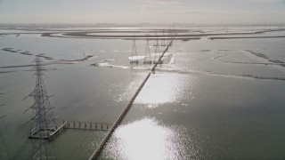 AXSF11_026 - 5K aerial stock footage of flying over marshland, tilt up, revealing power lines, Sunnyvale, California