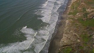 5K aerial stock footage fly away from waves rolling toward beach and cliffs in the Lakeshore District, San Francisco, California Aerial Stock Footage | AXSF15_033