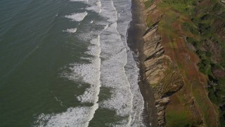 5K aerial stock footage of a reverse view of ocean waves rolling toward a beach and coastal cliffs, Lakeshore District, San Francisco, California Aerial Stock Footage | AXSF15_034