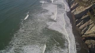 5K aerial stock footage of a reverse view of ocean waves rolling into coastal cliffs, Daly City, California Aerial Stock Footage | AXSF15_036