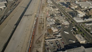 CAP_004_027 - HD stock footage aerial video reverse view of train between river and warehouses, Vernon, California