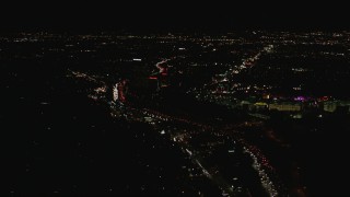 HD stock footage aerial video follow Highway 101 past Universal Studios Hollywood to approach the NBC Universal building at night, California Aerial Stock Footage | CAP_010_015