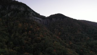 CAP_014_010 - 2.7K stock footage aerial video fly toward a waterfall at sunset, Chimney Rock, North Carolina