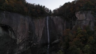 CAP_014_013 - 2.7K stock footage aerial video approach a clifftop waterfall at sunset, Chimney Rock, North Carolina