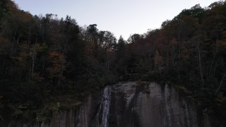 CAP_014_014 - 2.7K stock footage aerial video ascend over a clifftop waterfall at sunset, Chimney Rock, North Carolina