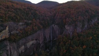 CAP_014_020 - 2.7K stock footage aerial video fly away from forest and a clifftop waterfall at sunset, Chimney Rock, North Carolina