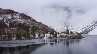 CAP_015_014 - 4K stock footage aerial video fly away from lake and snowy mountain slopes, Inyo National Forest, California