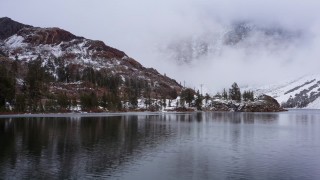 CAP_015_016 - 4K stock footage aerial video approach lake shore and snowy mountain slopes, Inyo National Forest, California