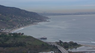 HD stock footage aerial video of flying toward Malibu Pier and oceanfront homes with a view of DTLA skyline at sunset, Malibu, California Aerial Stock Footage | CAP_018_051