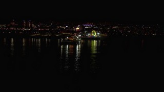 HD stock footage aerial video flying over the ocean toward the Ferris wheel and rides at nighttime, Santa Monica Pier, California Aerial Stock Footage | CAP_018_121