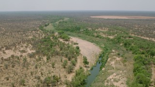 CAP_026_073 - HD stock footage aerial video of following a narrow river past trees in savanna, Zimbabwe